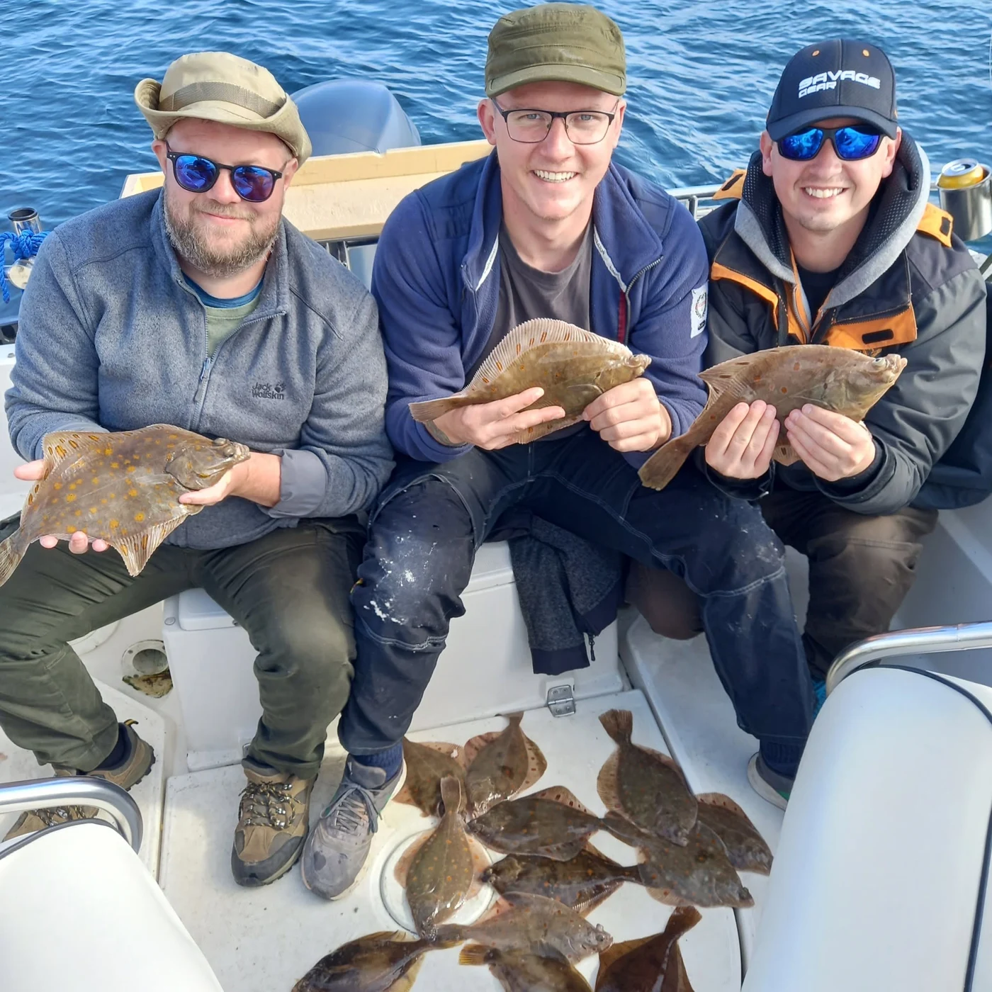 Tre glade fiskere med fladfisk ombord